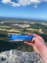Hand holding a Flow Recovery Bar with a scenic view of a landscape in the background